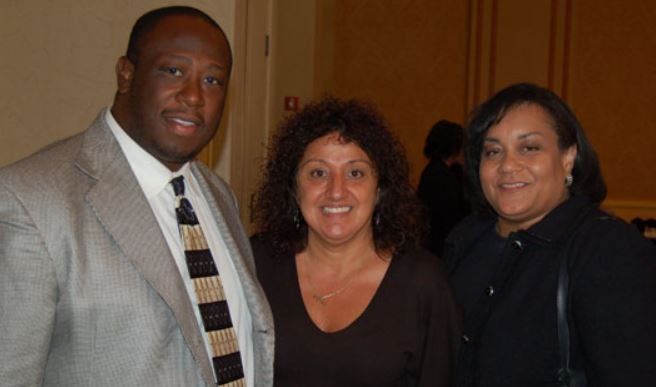 A man in a suit and tie poses with two women