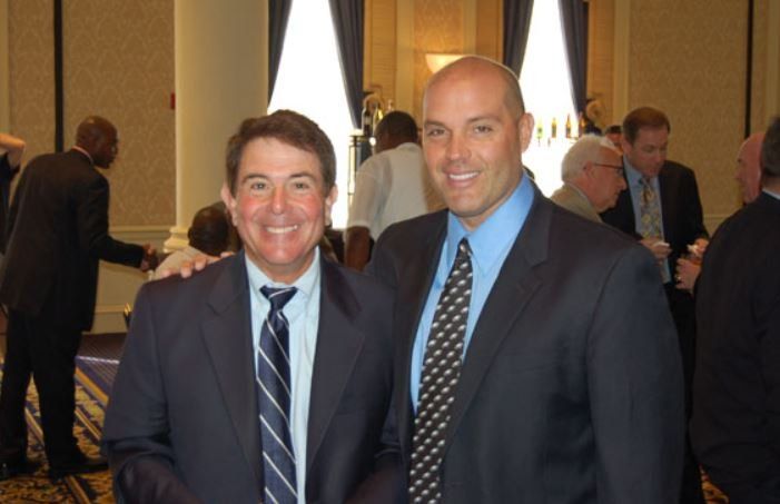 Two men in suits and ties are posing for a picture