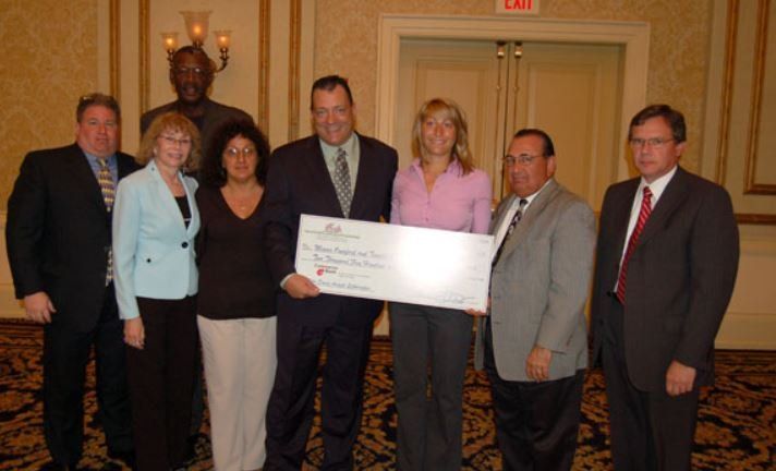 A group of people holding a large check in front of an exit sign