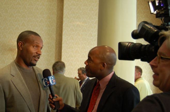 A man in a suit is being interviewed by a reporter with a microphone that says ge on it