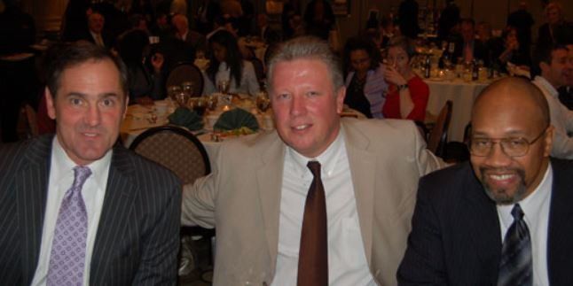 Three men in suits and ties are posing for a picture