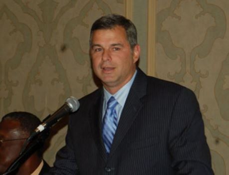A man in a suit and tie is speaking into a microphone