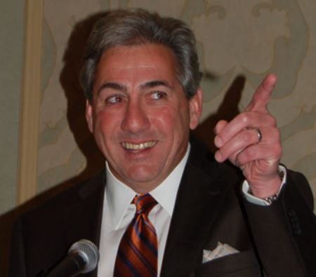 A man in a suit and tie is pointing up