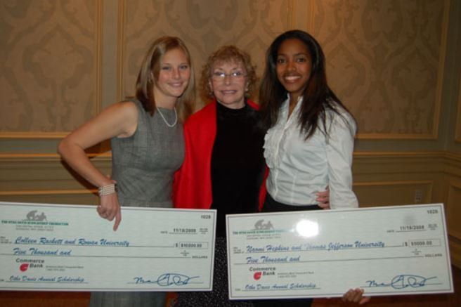 Three women are posing for a picture while holding large checks