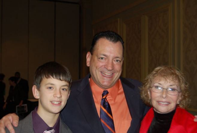 A man in a suit and tie poses with a boy and a woman
