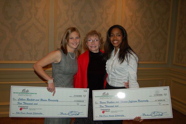 Three women standing next to each other holding large checks