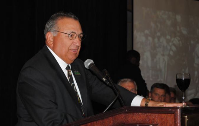 A man in a suit and tie is speaking into a microphone