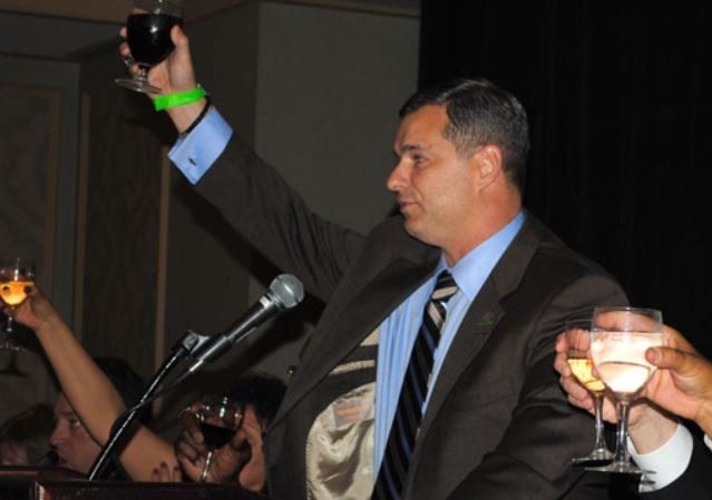 A man in a suit and tie holds up a glass of wine