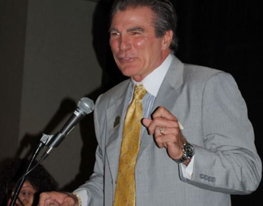 A man in a suit and tie is speaking into a microphone