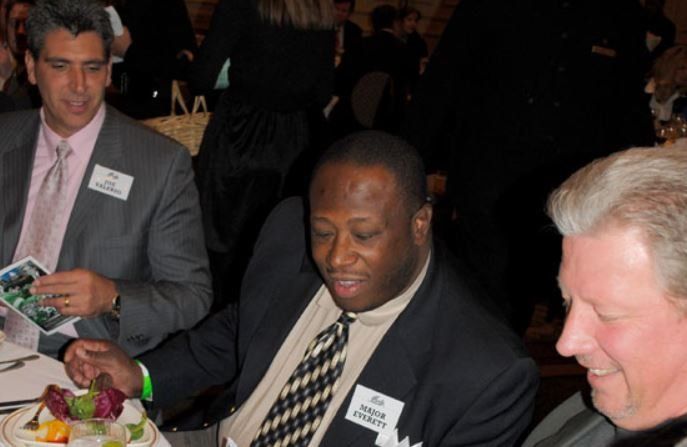 A man with a name tag that says ' rick ' on it sits at a table with other men