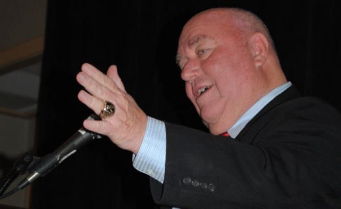 A man with a ring on his finger is speaking into a microphone