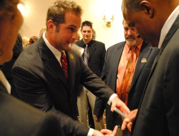 A group of men in suits and ties are gathered around a man in a suit