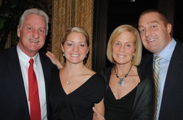 A man in a suit and tie poses with two women