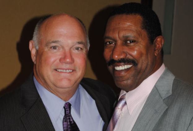 Two men in suits and ties are posing for a picture