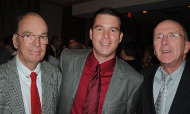 Three men in suits and ties pose for a picture