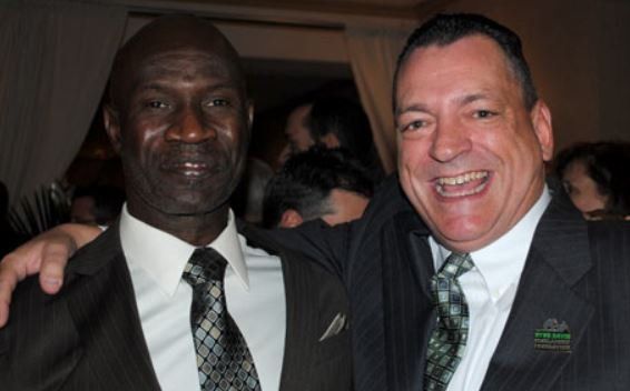 Two men in suits and ties pose for a picture