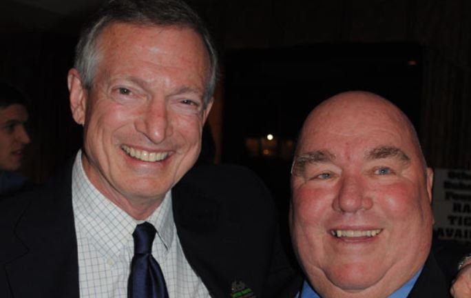 Two men are posing for a picture and smiling for the camera