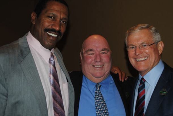 Three men in suits and ties are posing for a picture
