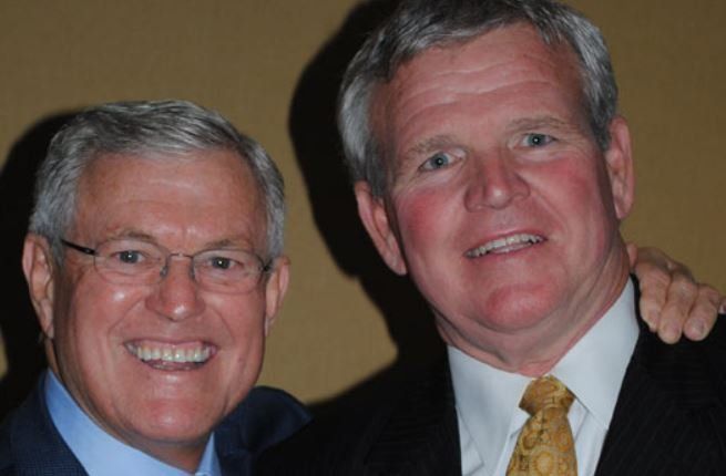 Two men are posing for a picture and one has his arm around the other 's shoulder