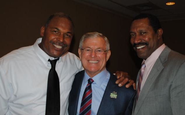 Three men posing for a picture with one wearing a tie