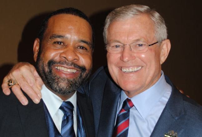 Two men are posing for a picture and one has his arm around the other 's shoulder