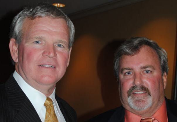 Two men in suits and ties are posing for a picture