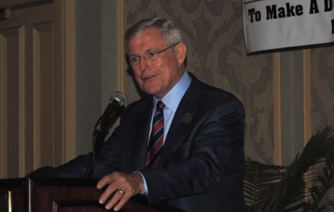 A man in a suit and tie is standing at a podium giving a speech