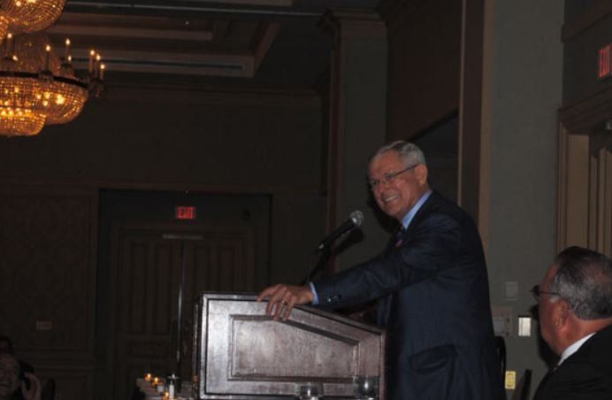 A man in a suit is giving a speech at a podium