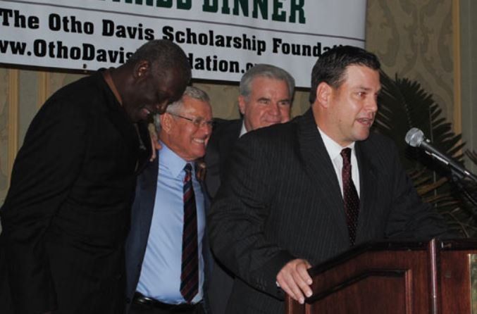 A group of men standing around a podium with a sign behind them that says dinner