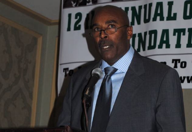 A man in a suit and tie is speaking into a microphone