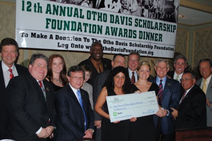 A group of people standing in front of a sign that says 12th annual otho davis scholarship foundation awards dinner