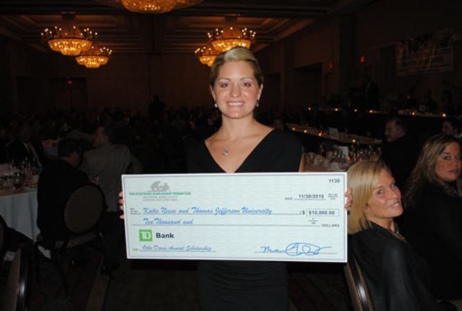 A woman in a black dress is holding a large check from td bank