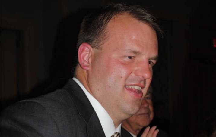 A man in a suit and tie is smiling for the camera