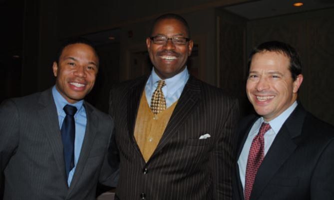 Three men in suits and ties pose for a picture
