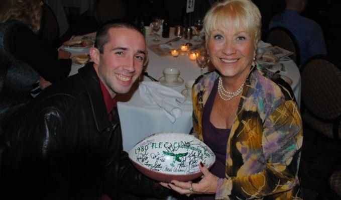 A man and a woman are sitting at a table holding a bowl that says 