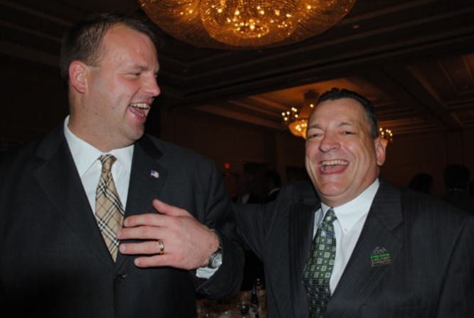 Two men in suits and ties are laughing together