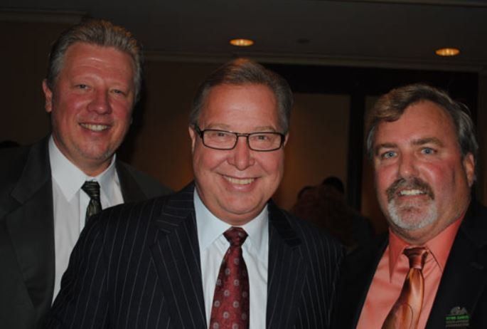 Three men in suits and ties are posing for a picture