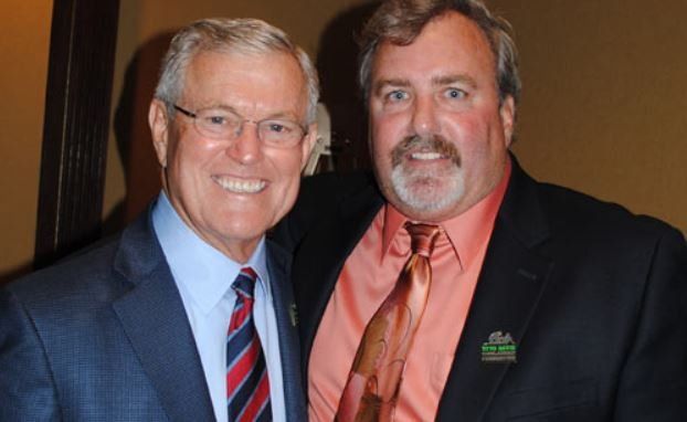 Two men in suits and ties are posing for a picture