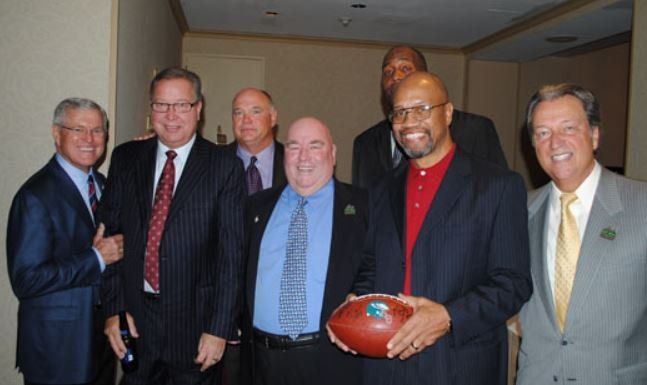 A group of men are posing for a picture and one man is holding a football