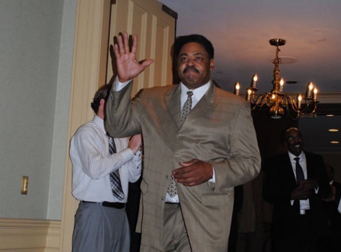 A man in a suit and tie is waving his hand