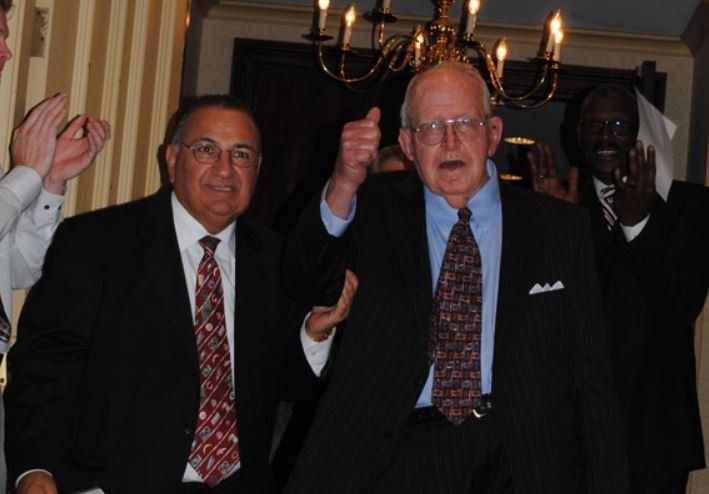 A man in a suit and tie is giving a thumbs up