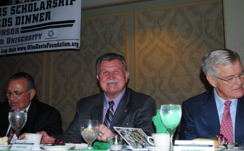Three men sit at a table in front of a sign that says scholarship awards dinner