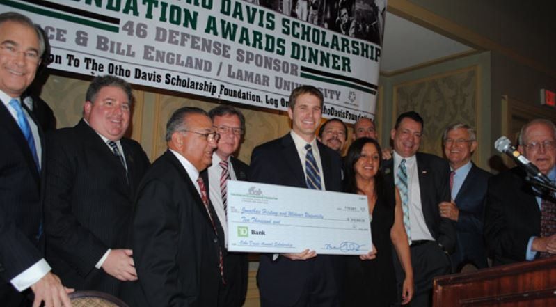A group of people standing around a podium holding a large check