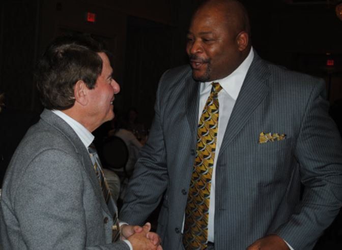 A man in a suit and tie shakes hands with another man