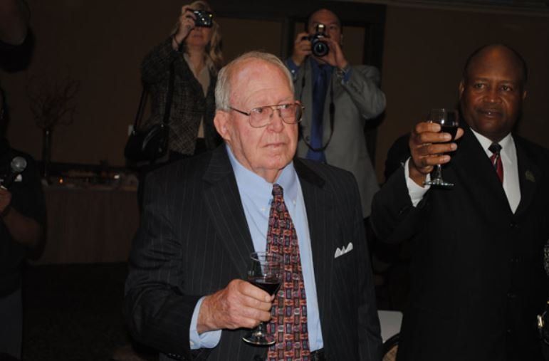 A man in a suit and tie is holding a glass of wine