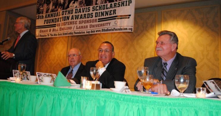 A group of men sit at a table in front of a sign that says ' foundation awards dinner '