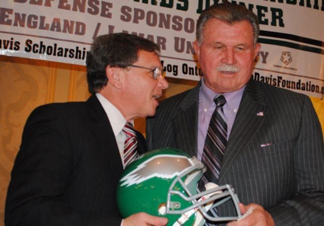 Two men are standing in front of a sign that says defense sponsor england