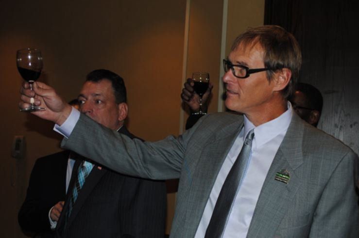 A man in a suit and tie is toasting with a glass of wine