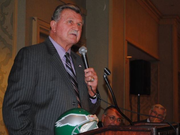 A man in a suit and tie is speaking into a microphone