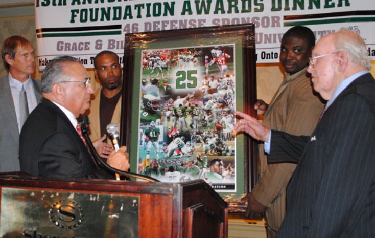 A man holding a framed picture with the number 25 on it